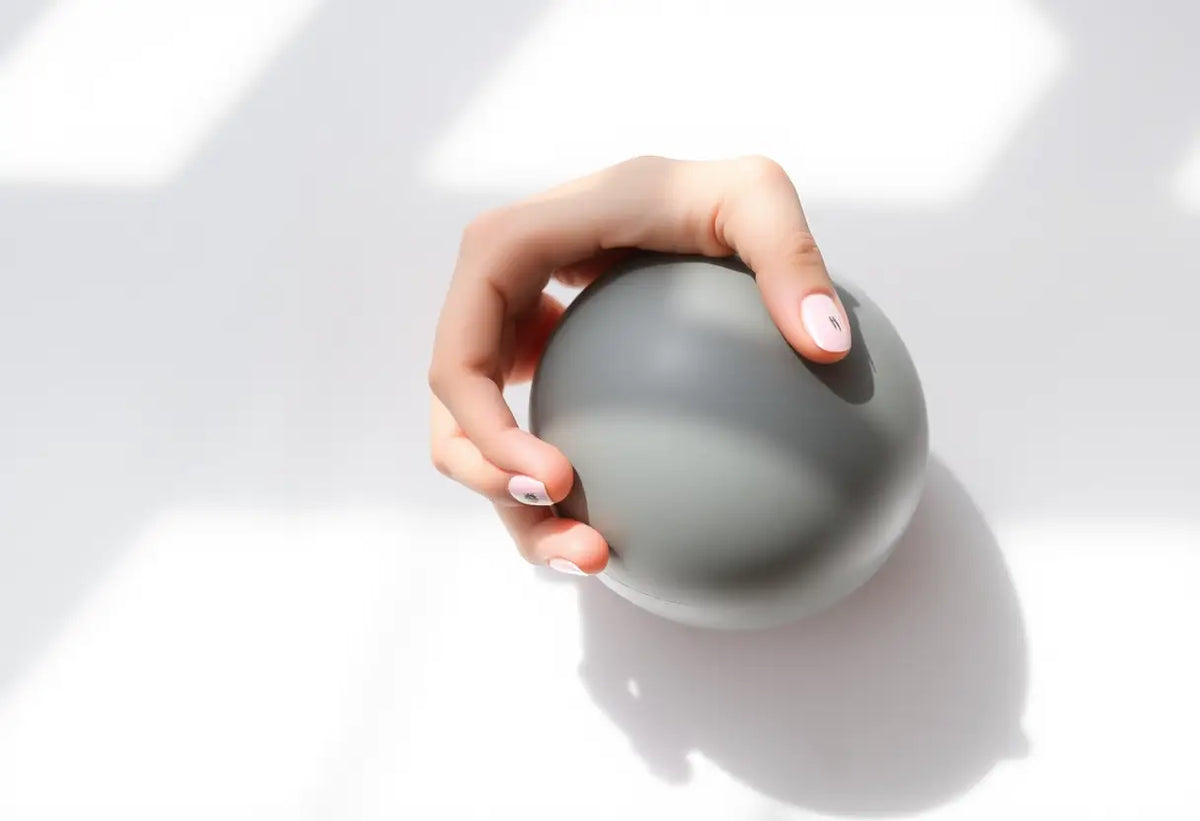 Main du sujet tenant une balle de gymnastique pour exercices périnéaux