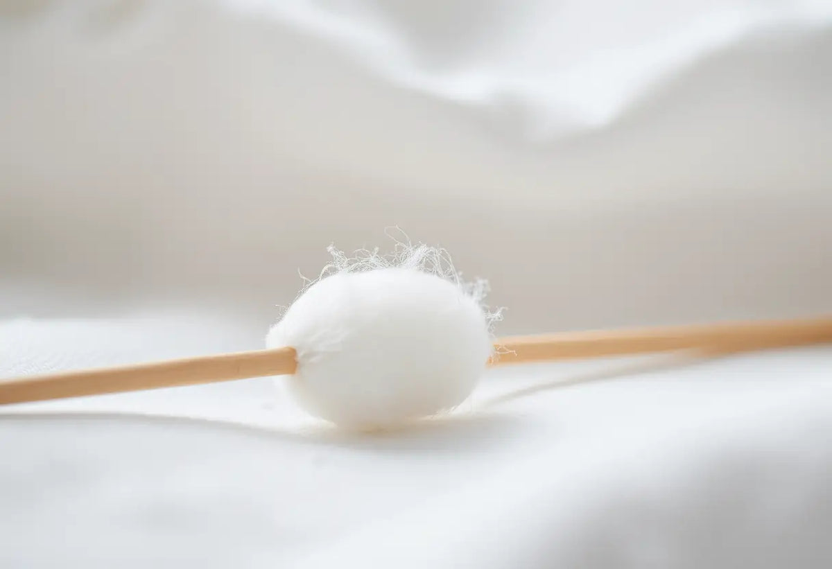 Un coton-tige posé sur un tissu blanc, rappelant la douceur nécessaire pour prendre soin de la vulve et du vagin.