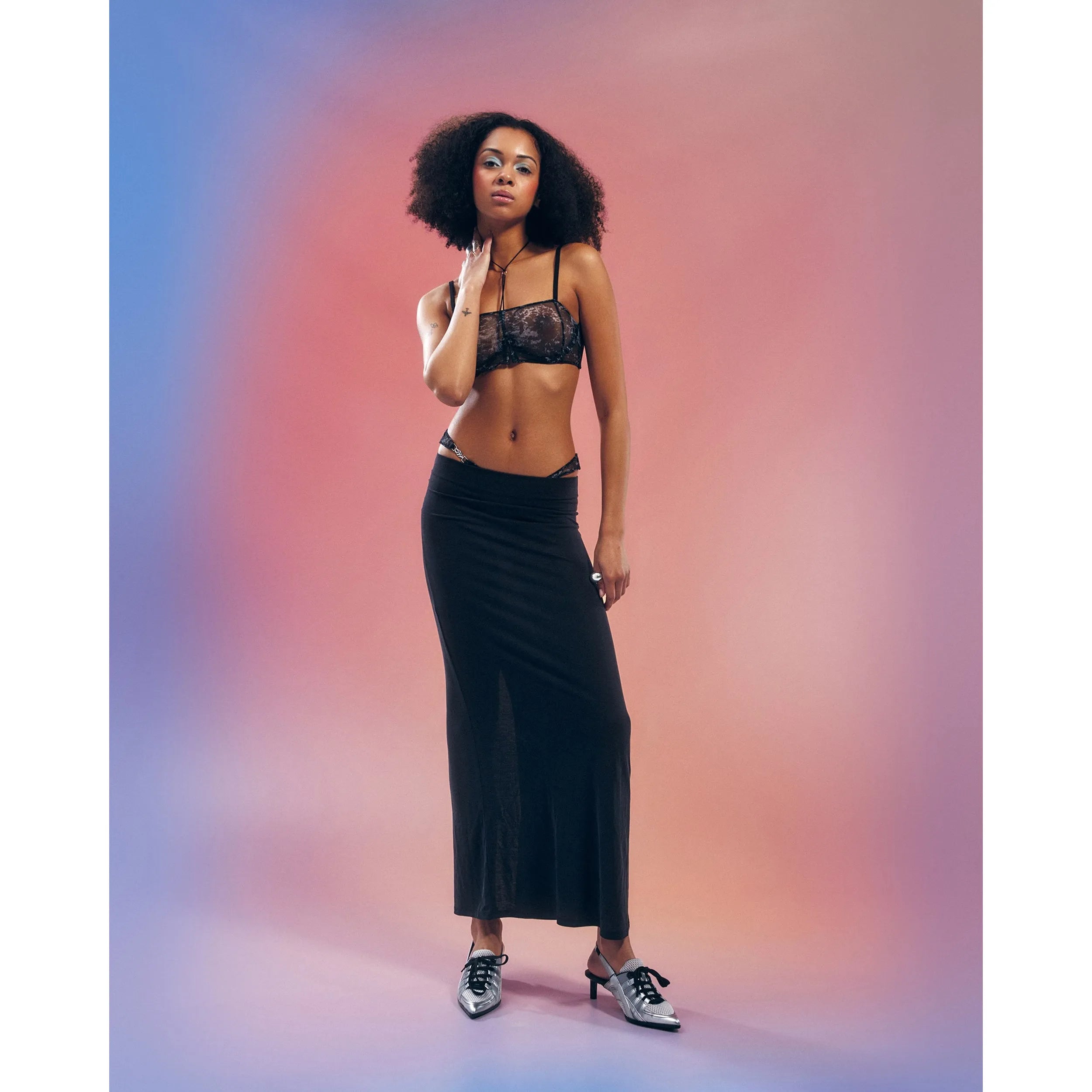 Soutien-gorge Corrosis noir transparent froncé, armatures réglables, motif raffiné, porté par mannequin, fond dégradé.