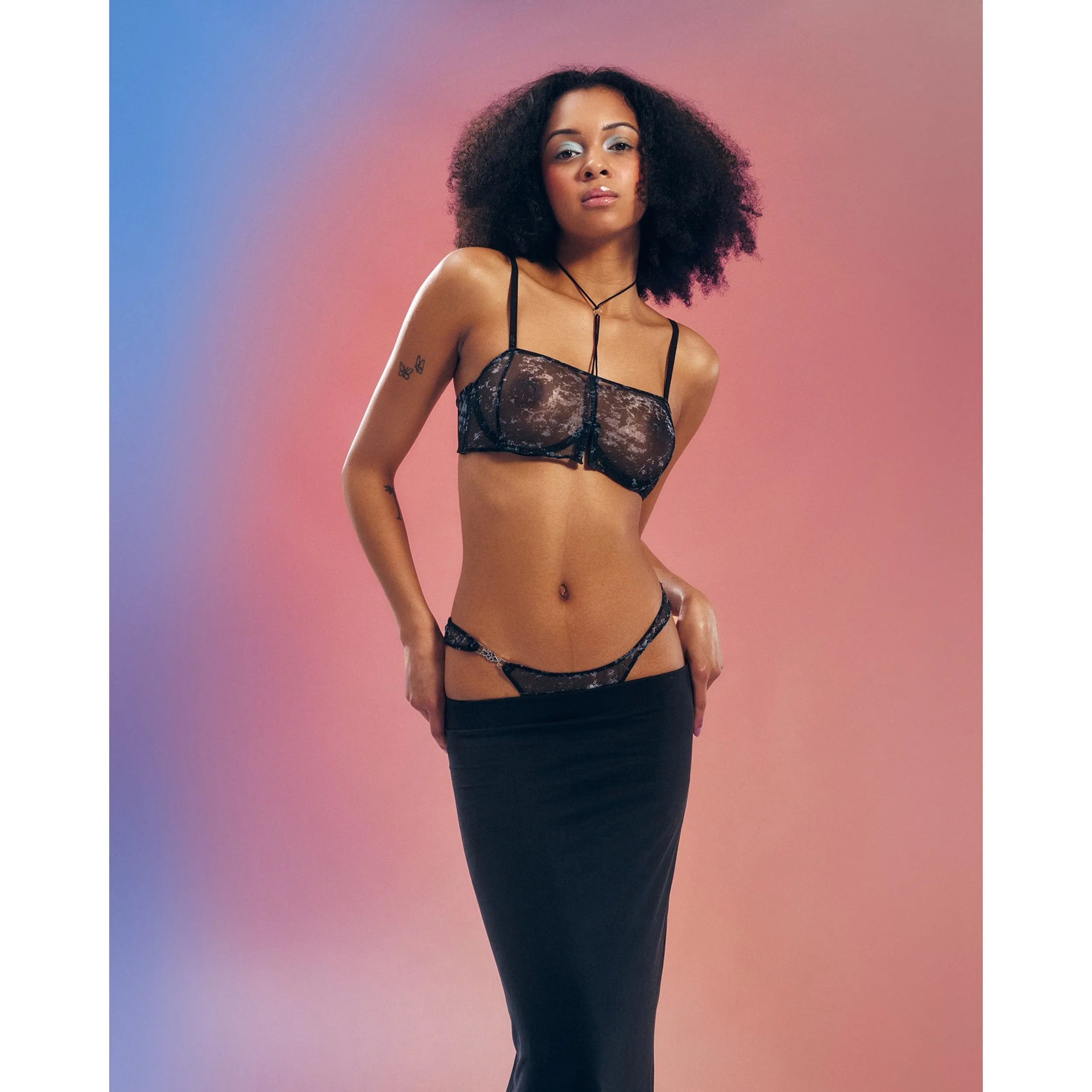 String ouvert argenté en maille transparente avec armatures, motif unique, porté par un mannequin sur fond dégradé.