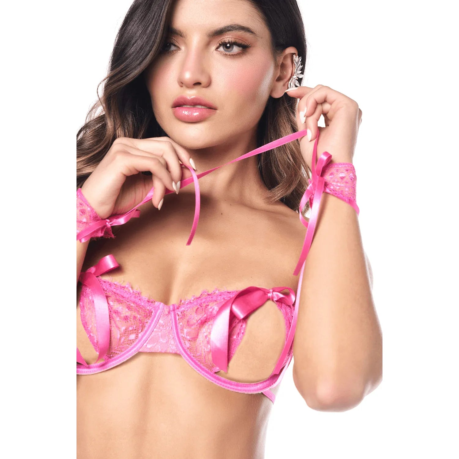 Ensemble lingerie rose vif en dentelle et satin, soutien-gorge ouvert, string, bandeau et menottes réglables.