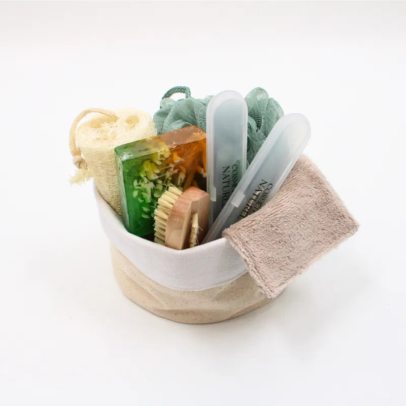 Coffret éco-rituel avec accessoires naturels biodégradables, brosse, savon coloré, éponge, et lingette dans un panier beige.