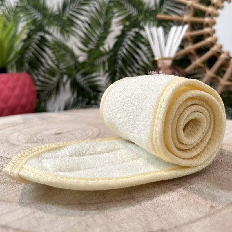 Bandeau cheveux crème en polyester, ajustable avec scratch, idéal pour maquillage et démaquillage, posé sur une table.
