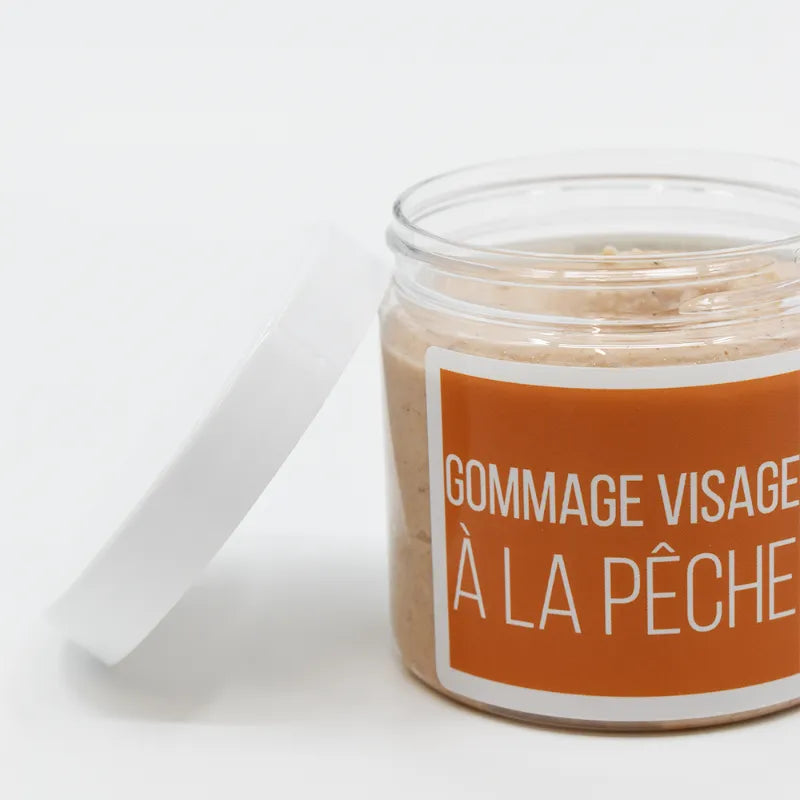 Gommage visage bio au noyau de pêche, pot transparent, exfoliant naturel, peau douce, soin éclatant, produit bio.