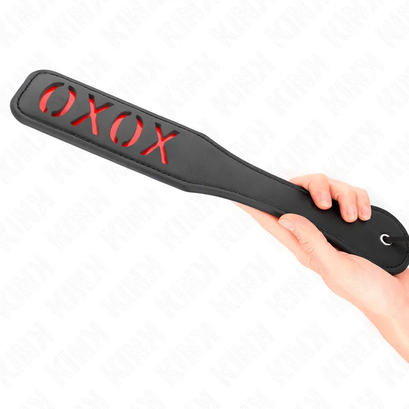 Accessoire BDSM en cuir noir avec découpe XOXO, poignée ergonomique, design élégant et sophistiqué.