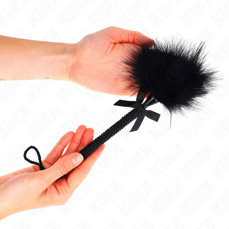 Accessoire BDSM plumeau noir en cuir véritable, élégant et raffiné, tenu en main, idéal pour expériences sensorielles.