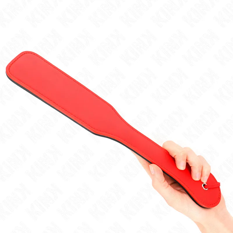 Accessoire BDSM en cuir rouge, pagaie élégante et durable, tenue en main, pour expériences sensuelles et raffinées.