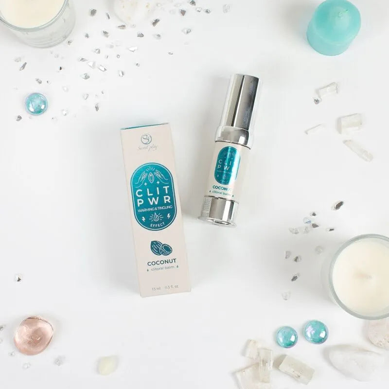 Baume stimulant clitoris chauffant, flacon argenté 15ml, boîte blanche et bleue, ambiance intime avec bougies.