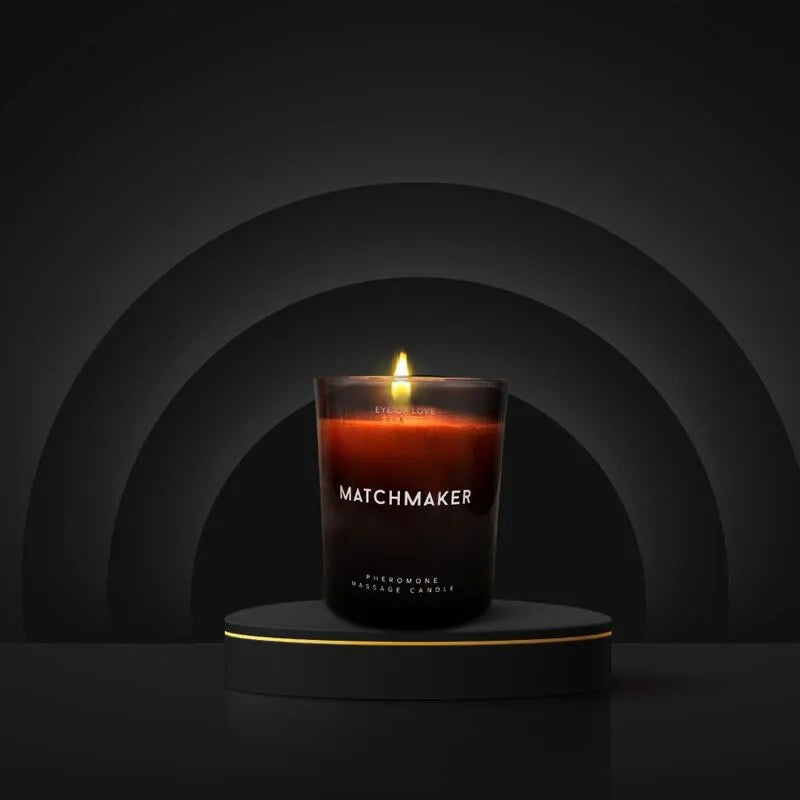Bougie massage phéromones noire allumée, parfum cèdre citron, sur socle élégant, ambiance détente et sensualité.