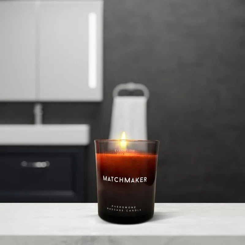 Bougie de massage phéromones, cire rouge, pot en verre noir, ambiance relaxante, parfum cèdre citron, salle de bain.