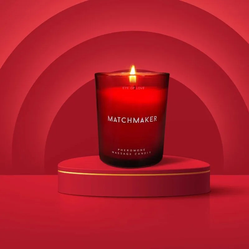 Bougie de massage rouge en verre, allumée, sur fond rouge, évoquant des notes de cèdre, cassis et citron.