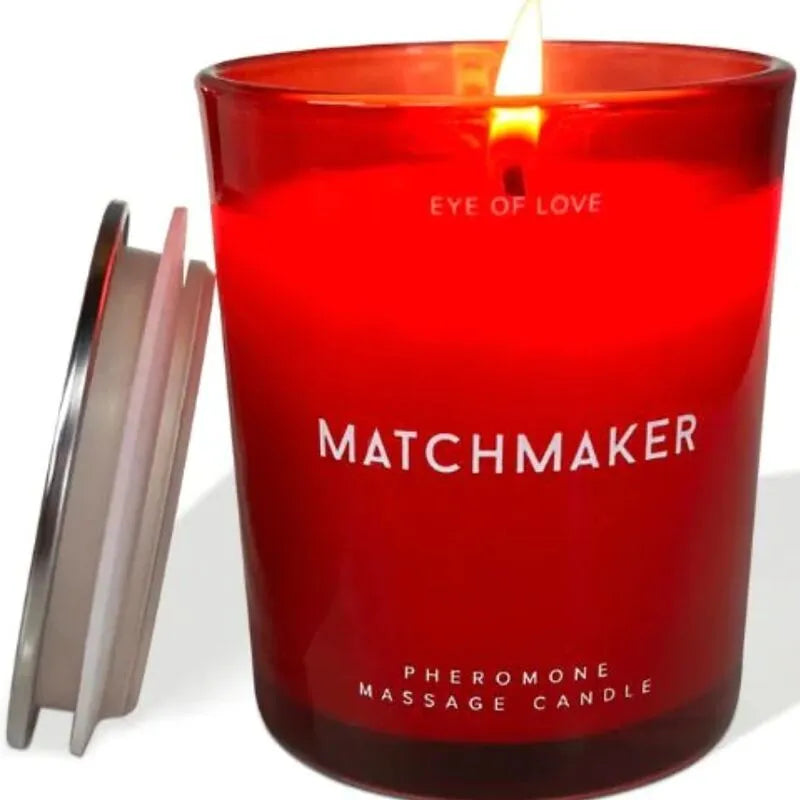 Bougie rouge allumée, étiquette Matchmaker, couvercle argenté, pour massage phéromones, parfum cèdre et cassis.