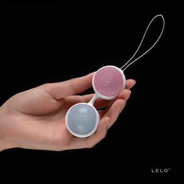 Boules Kegel ajustables en silicone rose et bleu pour renforcement pelvien post-partum, tenues dans une main.