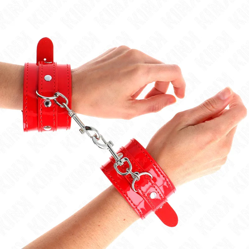 Bracelets BDSM rouges en cuir véritable, ajustables et reliés par une chaîne, pour expériences sophistiquées et confortables.