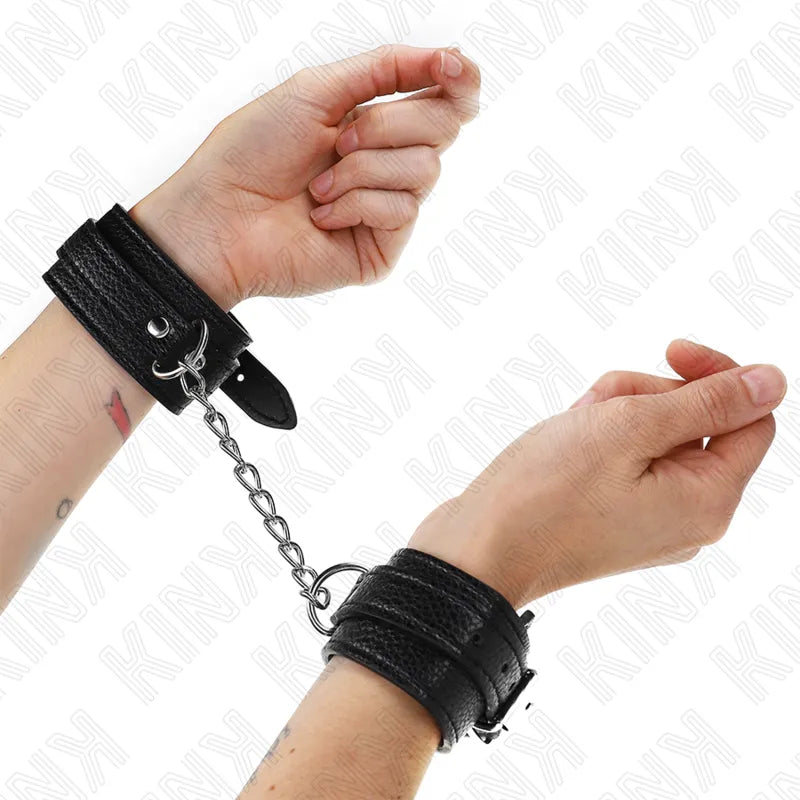 Bracelet BDSM en cuir noir ajustable avec boucles solides, rembourré pour confort, chaîne métallique entre les poignets.
