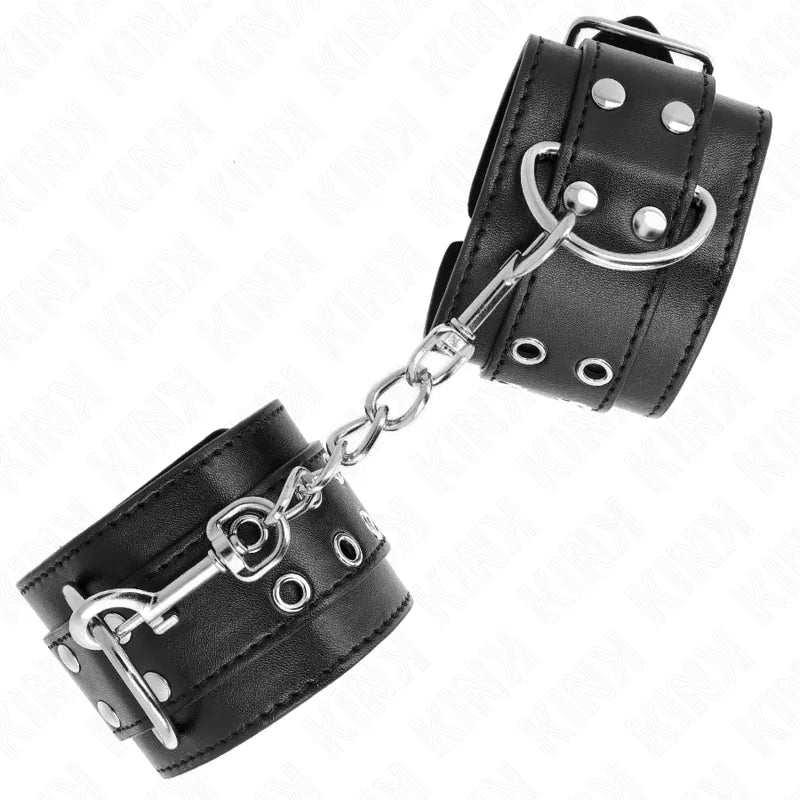 Bracelets BDSM cuir noir, boucles métalliques robustes, chaîne reliant, design élégant et sophistiqué, confort rembourré.