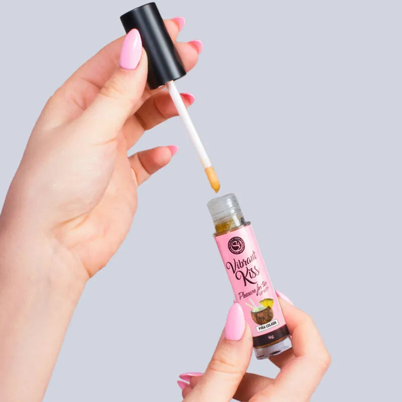 Brillant à lèvres vibrant Piña Colada, tube rose avec applicateur, ondes vibratoires, saveur exotique, mains féminines.