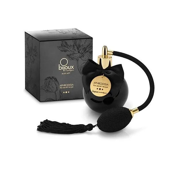 Brume corporelle sensuelle Bijoux Indiscrets, flacon noir élégant avec poire dorée, boîte noire florale, parfum ylang-ylang.