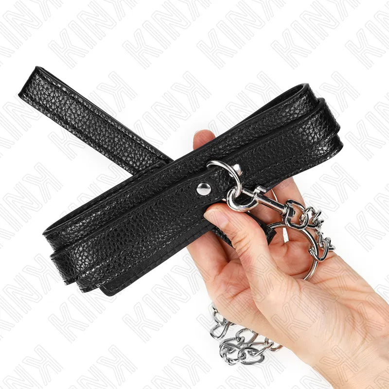 Collier BDSM en cuir noir végétalien, élégant et réglable, avec boucles métalliques et finition luxe, tenu en main.