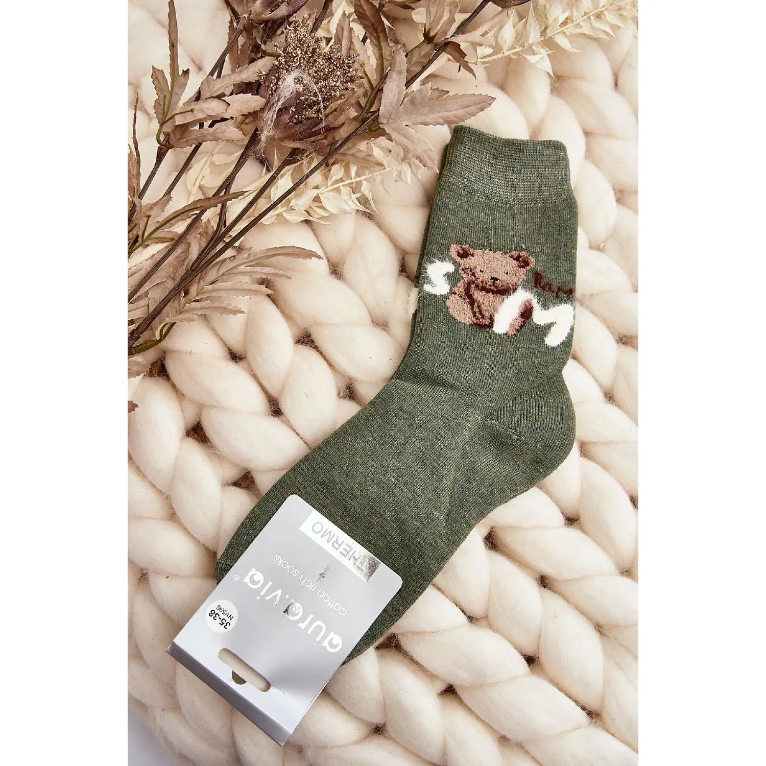 Chaussettes vertes en coton avec patch ourson, trépointe ajustée, posées sur fond de laine, idéales pour journées froides.