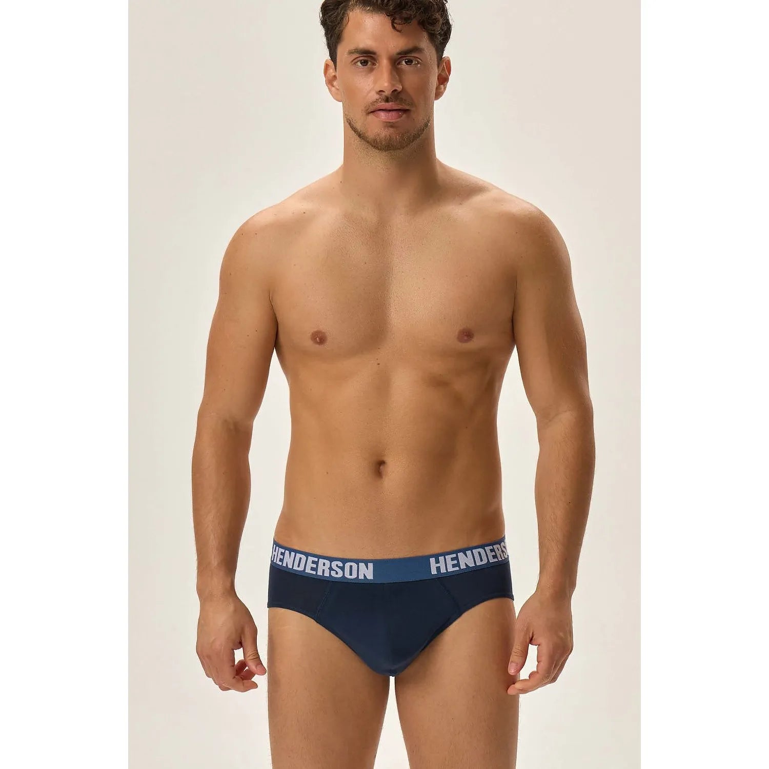 Homme portant slip Henderson bleu foncé avec ceinture élastique large logo contrastant, coupe classique, fond blanc.