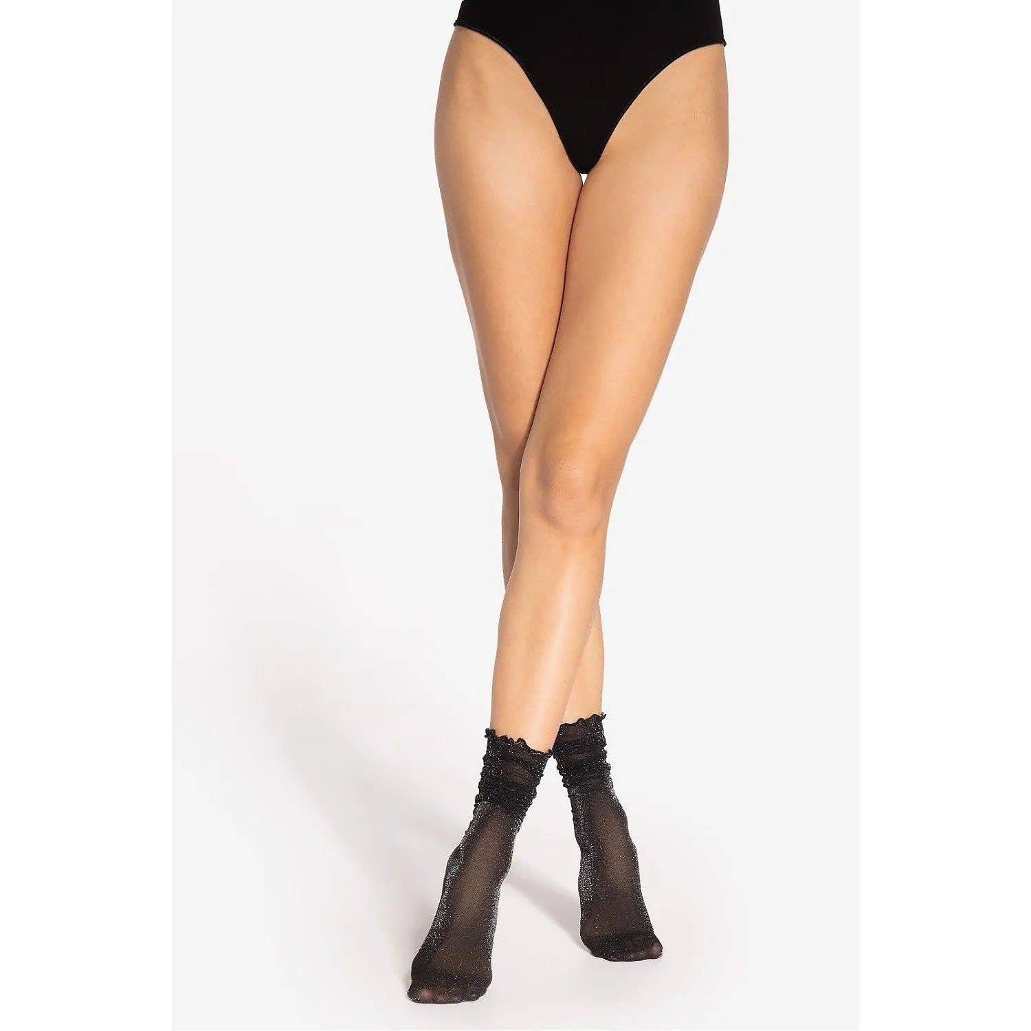 Chaussettes transparentes noires scintillantes en nylon avec volant subtil, portées sur chevilles, élégance et confort.