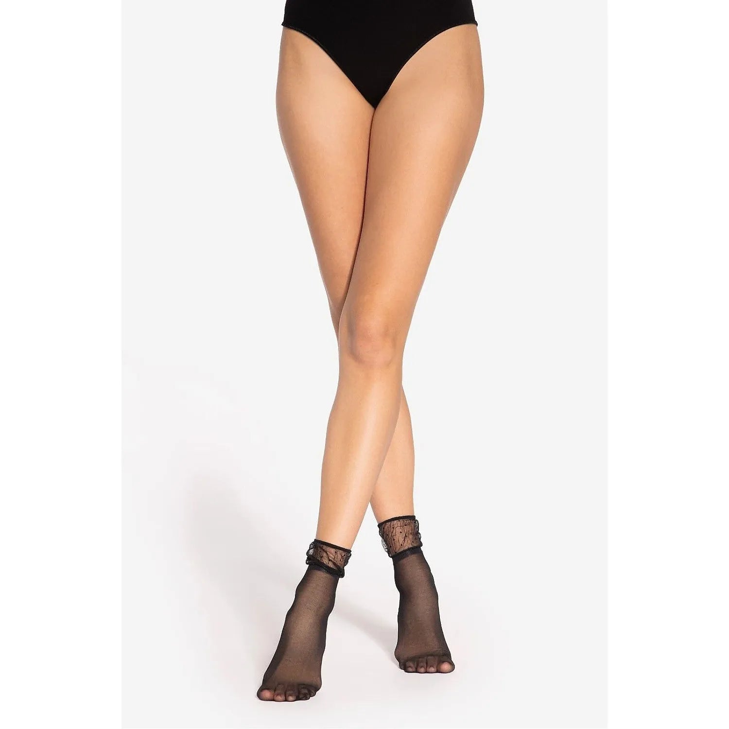 Chaussettes transparentes noires en dentelle avec motifs floraux, élégantes et sensuelles, portées sur jambes croisées.