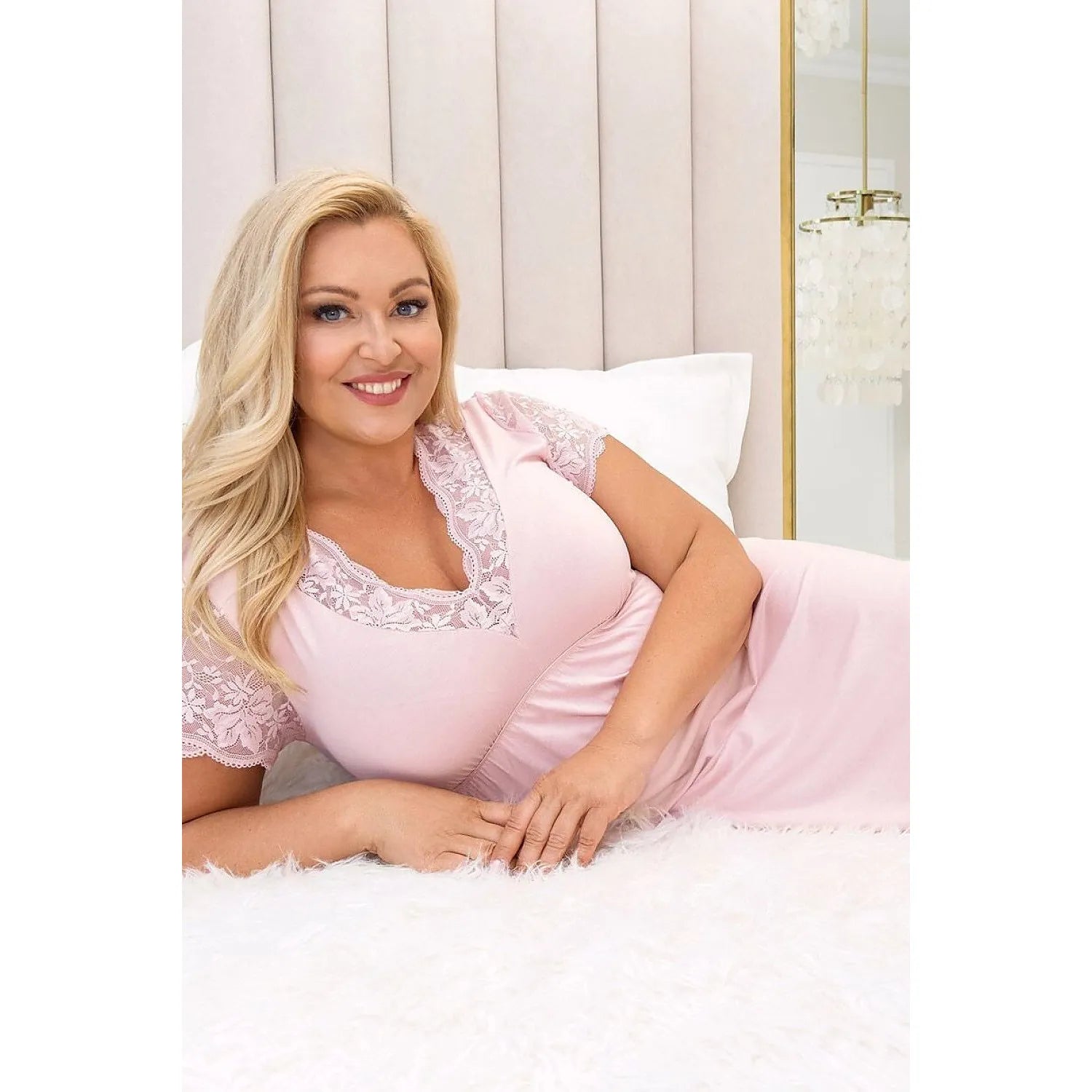 Chemise de nuit rose dentelle Plus Size Sonia, manches courtes, élégante et confortable, femme allongée sur lit.