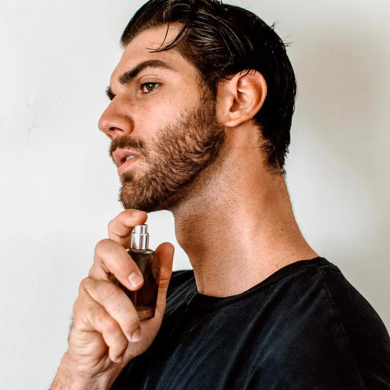 Homme appliquant eau de cologne phéromones, flacon élégant, séduction masculine, notes terreuses et citronnelle.