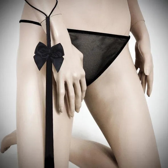 Fouet à franges noires douces Bijoux Indiscrets, design élégant avec nœud, pour caresses sensuelles et jeux raffinés.