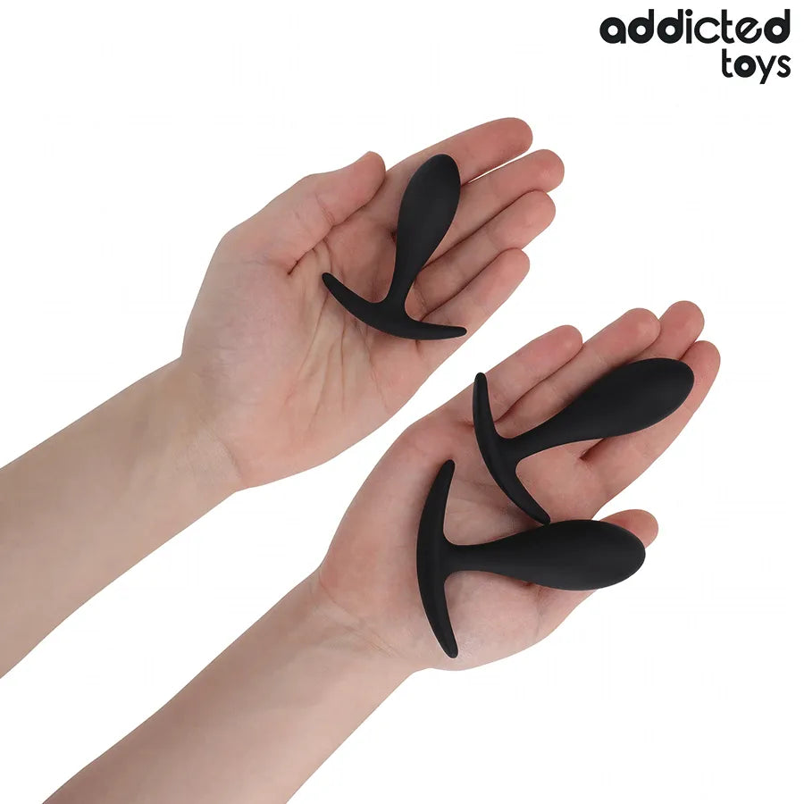 Lot de 3 plugs anal noirs en silicone médical, tailles progressives, base ancre, Addicted Toys, sur fond blanc.