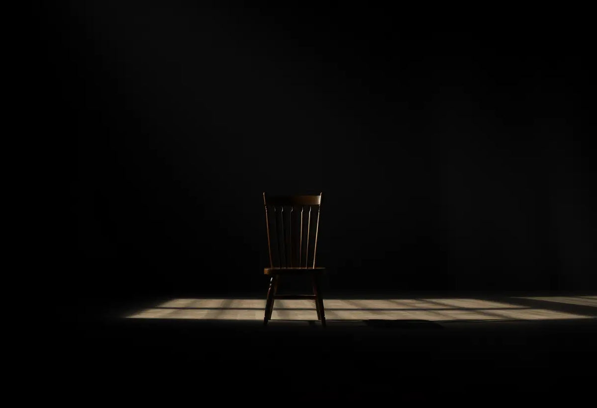 Un fauteuil vide dans une pièce sombre, représentant la réflexion sur la bisexualité
