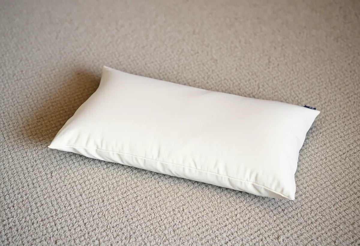 Coussin moelleux posé sur un tapis, symbolisant confort et détente lors des exercices de plancher pelvien