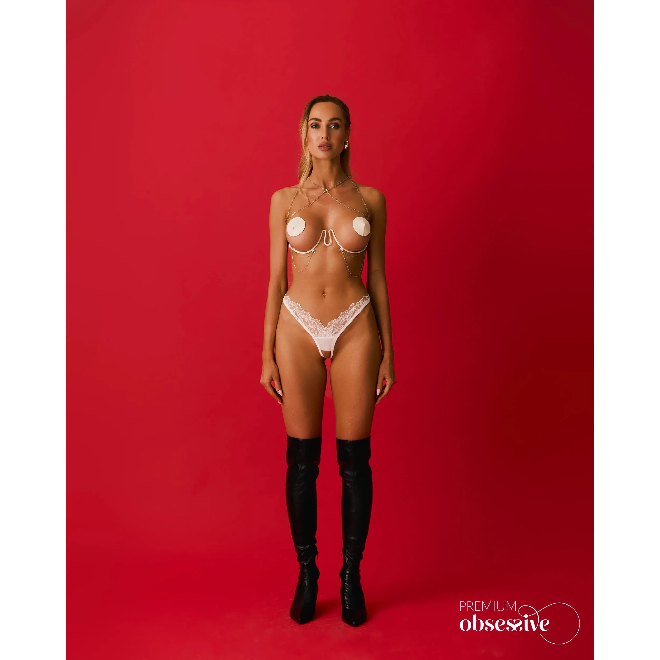 Harnais soutien-gorge blanc avec chaînes argentées, sous-buste désossé, ajustable, sur fond rouge.