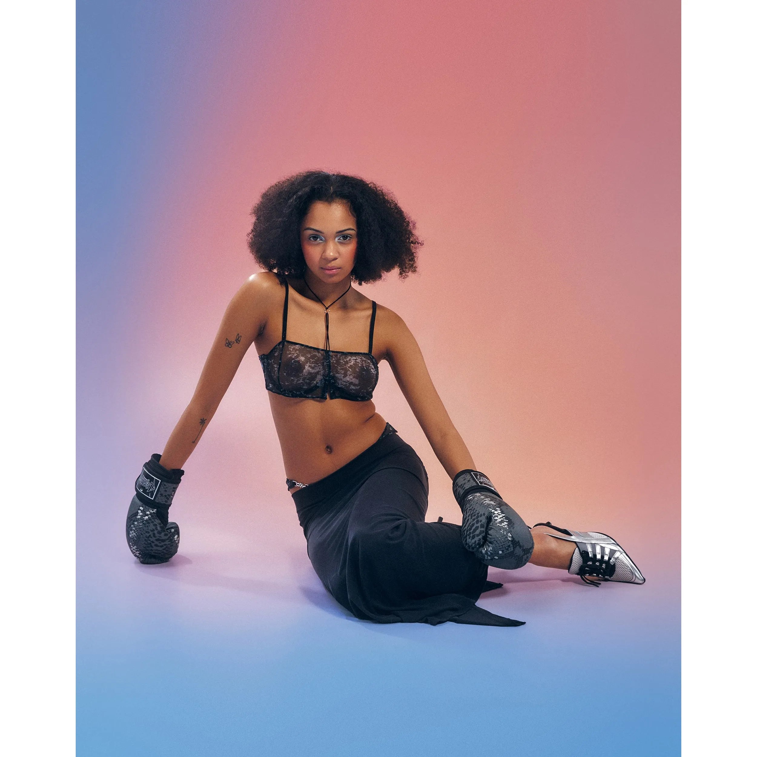 Soutien-gorge Corrosis transparent noir froncé, armatures réglables, motif raffiné, porté par modèle sur fond dégradé.