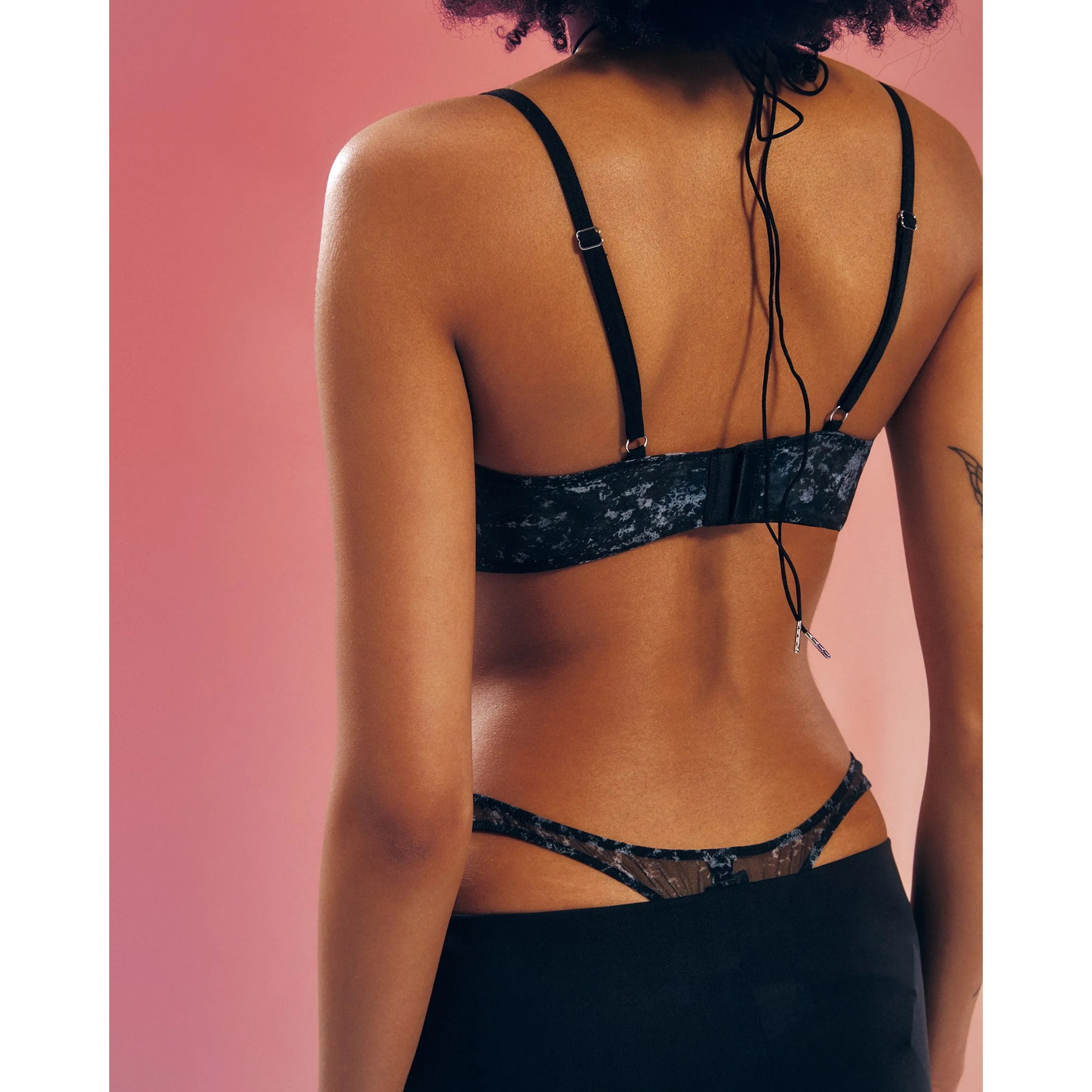 String ouvert argenté en maille transparente avec motif unique, armatures soutien, sur fond rose.