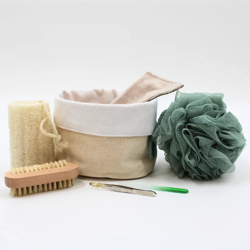 Coffret beauté zéro déchet avec accessoires réutilisables en coton beige, éponge verte, brosse bois, et loofah naturel.