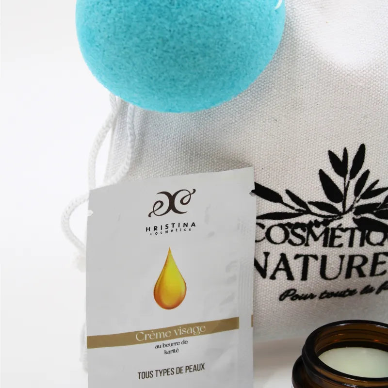 Coffret soins naturels peaux sensibles avec crème visage, éponge bleue et pot en verre, sur fond blanc.