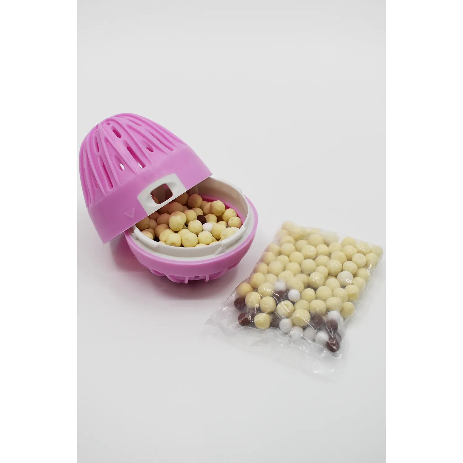 Boule de lavage écologique rose ouverte avec billes hypoallergéniques, recharge printanière visible à côté.