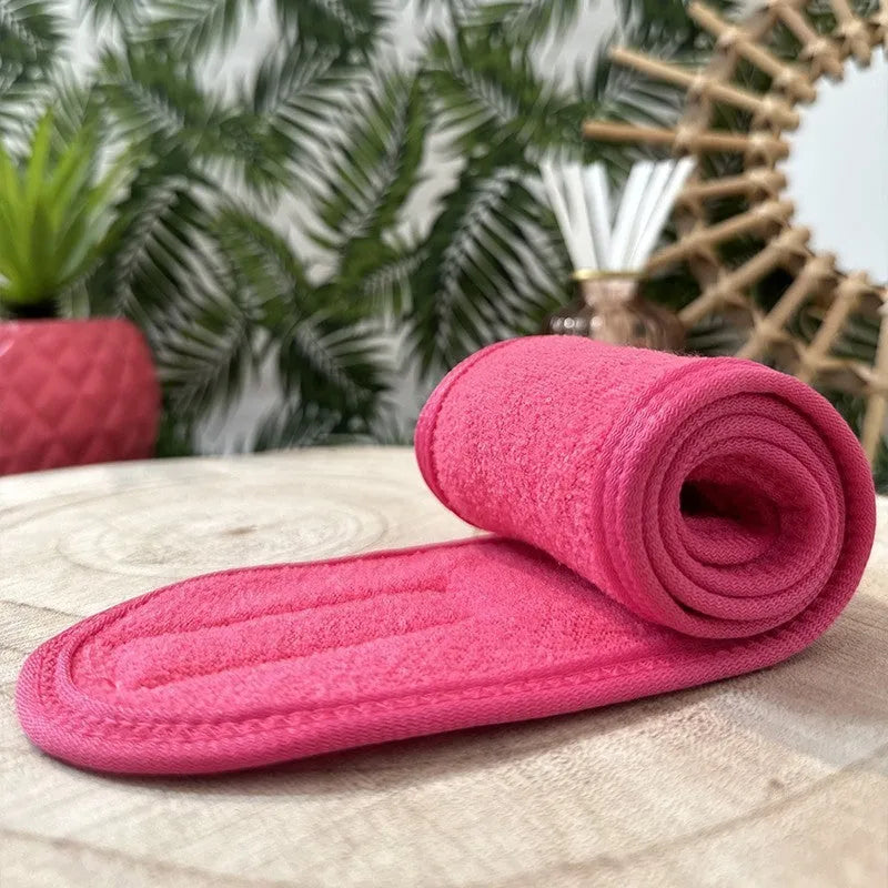 Bandeau cheveux rose en polyester doux, ajustable par scratch, idéal maquillage et démaquillage, posé sur table.