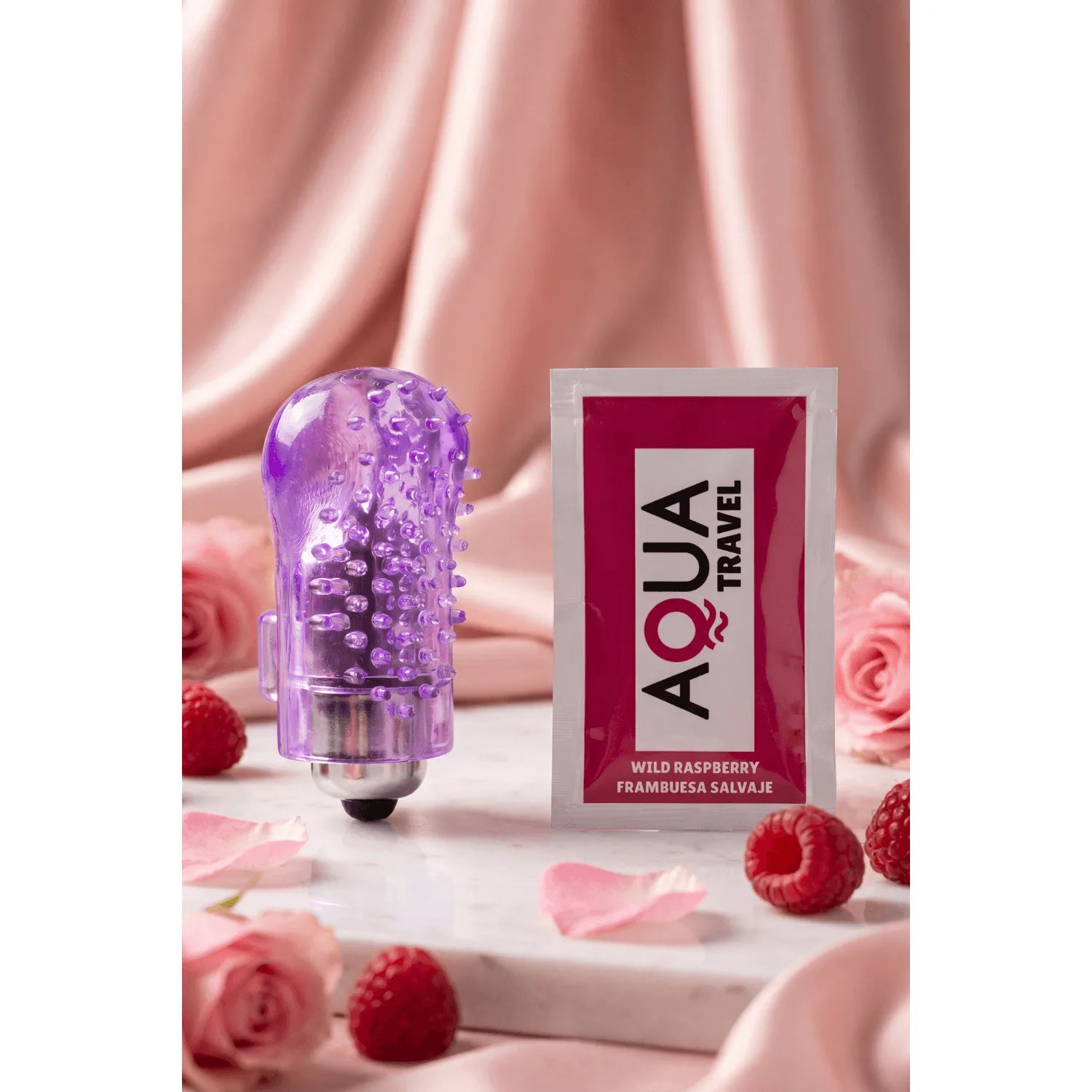 Doigt vibrant violet translucide avec manchon texturé et bullet puissant, posé près d'un sachet Aqua Travel.