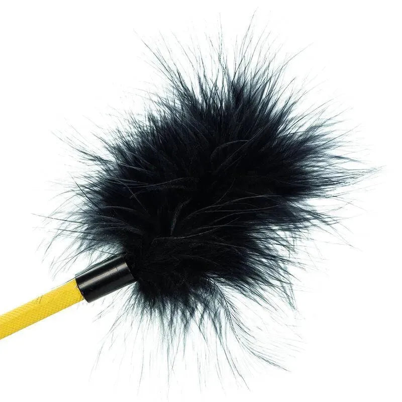 Accessoire BDSM plume noire en fausse fourrure sur manche jaune, 53cm, élégant et sensoriel pour moments intimes raffinés.