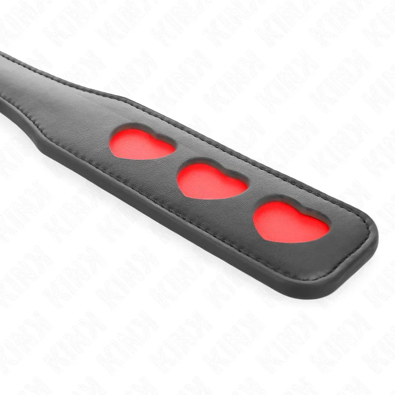 Accessoire BDSM en cuir noir avec découpes cœur rouges, design élégant et sophistiqué pour séances sensuelles.