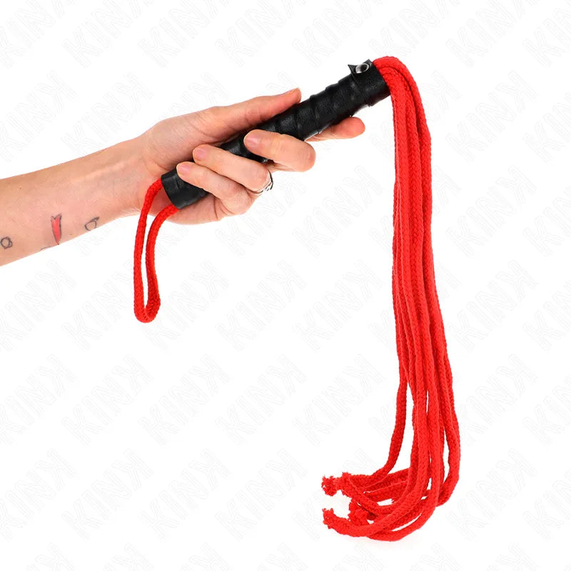 Main tenant un fouet BDSM rouge et noir en cuir et silicone, élégant et robuste, idéal pour jeux érotiques raffinés.