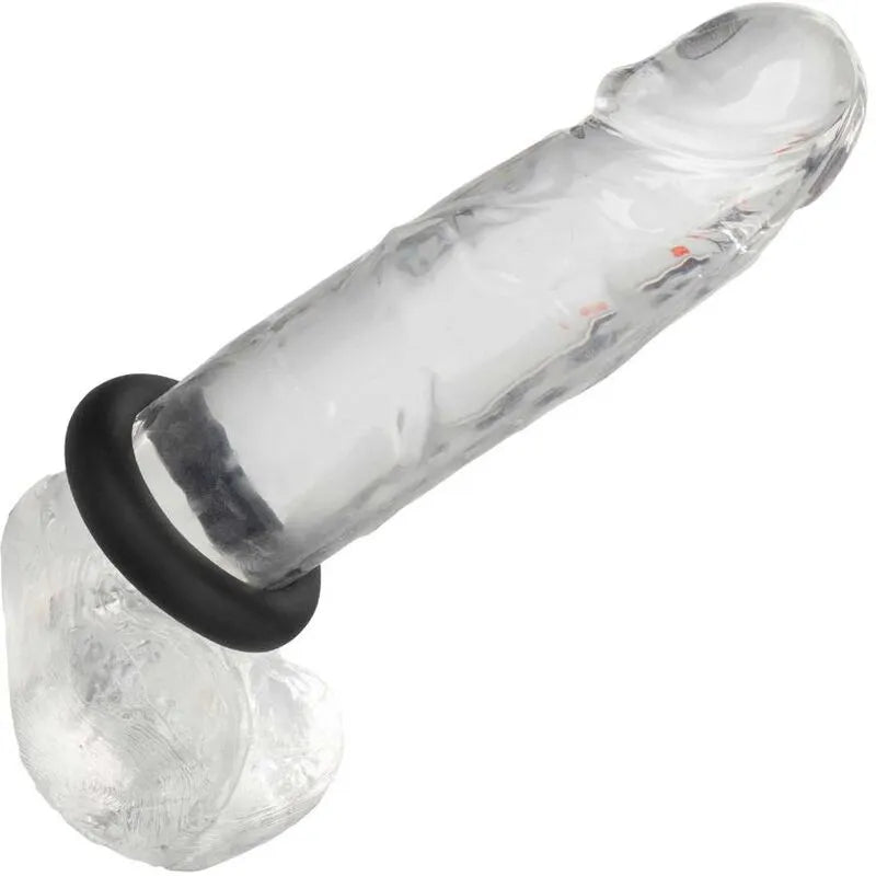 Anneau silicone liquide noir extensible sur objet transparent, design lisse et durable pour performance intime optimale.