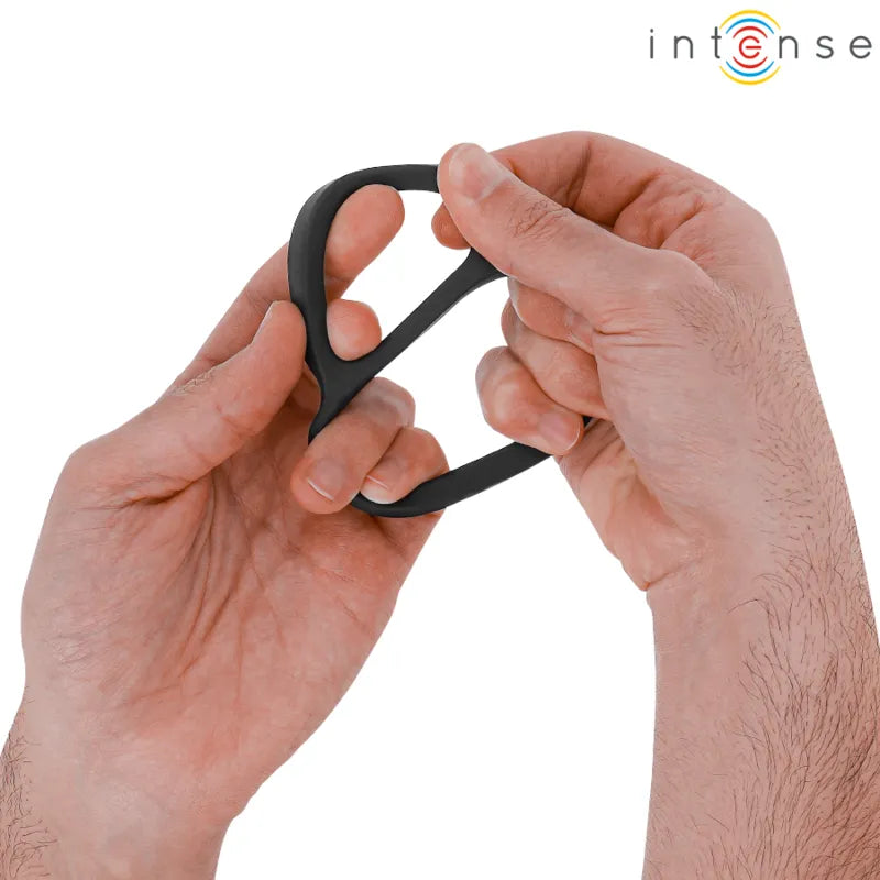 Anneau double silicone noir ergonomique, flexible, tenu par des mains, design compact pour confort et sécurité intimes.
