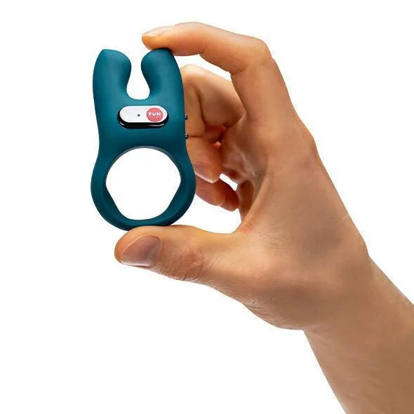 Anneau pénien vibrant bleu en silicone, ergonomique et flexible, tenu par une main, avec bouton tactile visible.