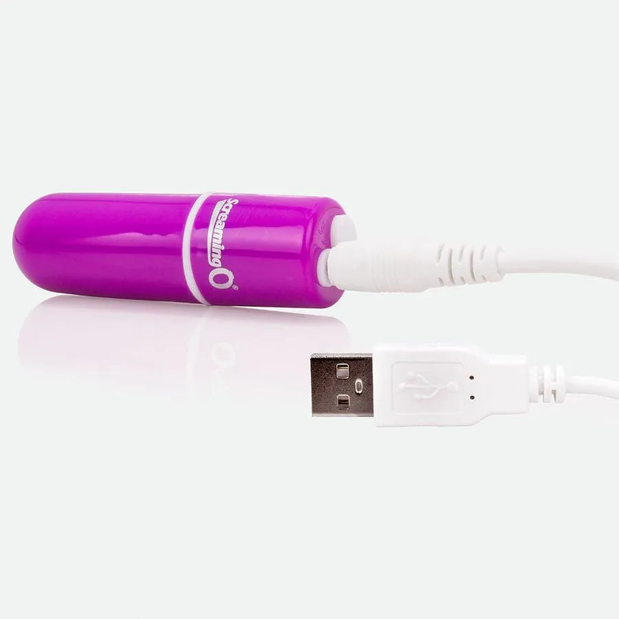 Balle vibrante lilas compacte, submersible, en silicone douce, avec câble USB blanc pour recharge.