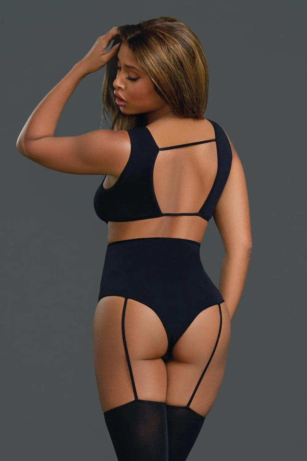 Bodystocking noir opaque moulant avec jarretelles et ornements croisés, style culotte haute et boléro, élégant et sensuel.