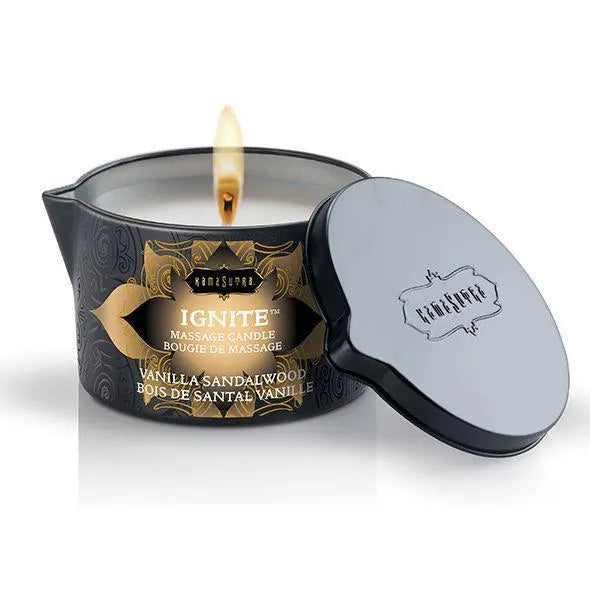 Bougie de massage érotique bois de santal, pot noir, flamme allumée, couvercle à côté, ambiance sensuelle et relaxante.